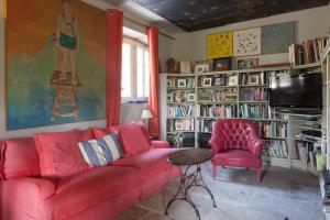 a living room with a red couch and a tv at Mas de Baubesse: Paradise in Provence in Les Baux-de-Provence