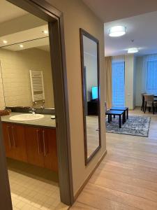 een badkamer met een spiegel en een wastafel en een woonkamer bij Lodge Euphoria Apartment in Borovets