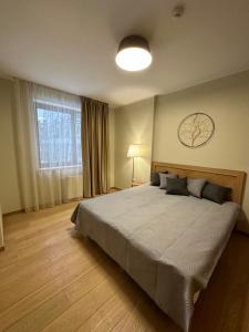 a bedroom with a large bed with a clock on the wall at Lodge Euphoria Apartment in Borovets