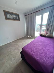 1 dormitorio con cama morada y ventana grande en Departamento Duplex B° Nueva Cordoba en Córdoba