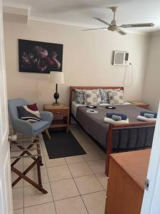 a bedroom with a bed and a chair and a table at City centre, tropical home, minutes walk to shops. in Cairns