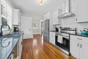 uma cozinha com armários brancos e electrodomésticos de aço inoxidável em Beautiful Historical home in Fisher Park! 4BR 3BA em Greensboro