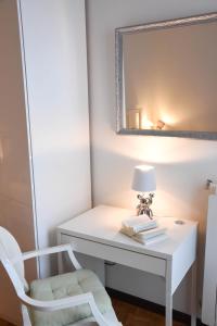 una scrivania bianca con sedia, lampada e specchio di FLAT 33 - Pool, Park, Tennis a Lavena Ponte Tresa