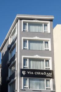 Un edificio grigio alto con un cartello sopra di Via Çırağan Hotel a Istanbul