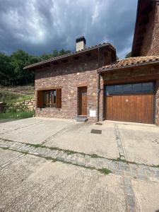un edificio de ladrillo con garaje y puerta de madera en Relax en el Pirineo, en Montanúy