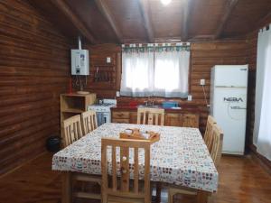 eine Küche mit einem Tisch mit Stühlen und einem Kühlschrank in der Unterkunft CABAÑAS LAS ACACIAS in Colonia Las Rosas