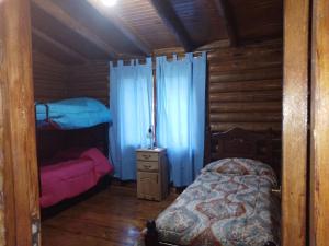 a bedroom with a bed in a wooden cabin at CABAÑAS LAS ACACIAS in Colonia Las Rosas