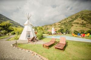 a group of chairs and a windmill next to a pool at Cerro Tusa Glamping in Titiribí