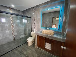 a bathroom with a sink and a toilet and a mirror at HOTEL EL CORAL in Punta Mita