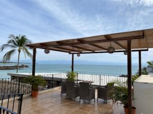 een patio met een tafel en stoelen en de oceaan bij HOTEL EL CORAL in Punta Mita