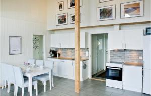 una cocina con armarios blancos y una mesa con sillas. en Lovely Home In Farsund With House A Mountain View, en Herad