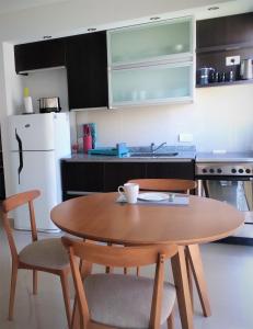 una cocina con mesa de madera y sillas y una cocina con nevera blanca. en Blue Bird Studio Baires en Buenos Aires