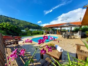 - une piscine avec bancs en bois et fleurs sur une terrasse dans l'établissement Pousada Pé na Montanha, à Socorro