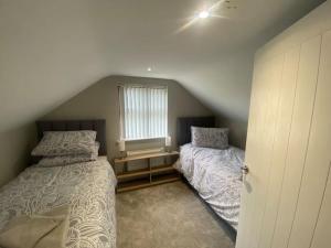 a attic bedroom with two beds and a window at Country Cottage close to the city. in Newry