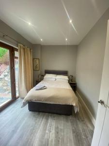 a bedroom with a bed and a large window at Country Cottage close to the city. in Newry