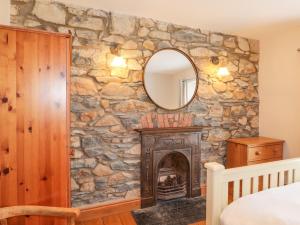 a stone wall with a fireplace in a bedroom with a mirror at Carnorfa in Newport Pembrokeshire