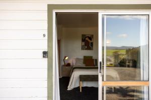 una puerta corredera de cristal que conduce a un dormitorio con cama en GLENALMOND Historic Homestead & Alpine Country Stay en Harihari