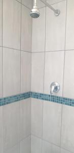 a shower with a white tiled wall and a shower head at Private Room Chez Khanyi Homestays in Pretoria