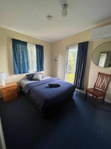 een slaapkamer met een bed, een stoel en een spiegel bij 3 bedroom house in great location in Goondiwindi