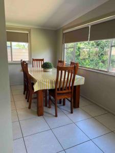 comedor con mesa, sillas y ventanas en 3 bedroom house in great location, en Goondiwindi