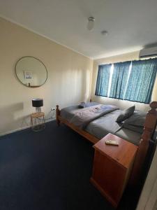 een slaapkamer met een bed, een tafel en een spiegel bij 3 bedroom house in great location in Goondiwindi