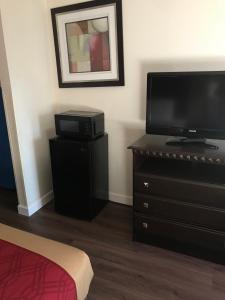 a bedroom with a flat screen tv and a dresser with a television at The Best Inn & Suites in Markham