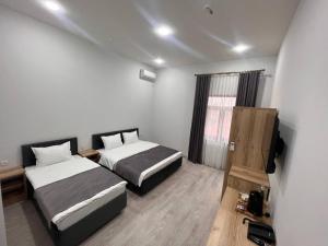 ein Hotelzimmer mit zwei Betten und einem Fernseher in der Unterkunft Rever Hotel in Taschkent