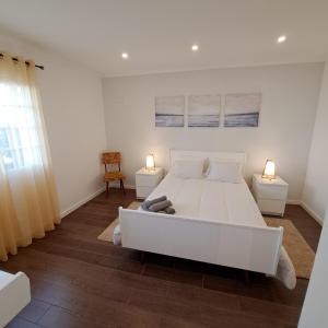 a bedroom with a large white bed and two lamps at Hamilton House in Vila Franca do Campo