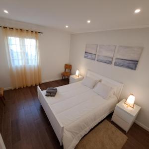 a white bedroom with a large white bed and two lamps at Hamilton House in Vila Franca do Campo