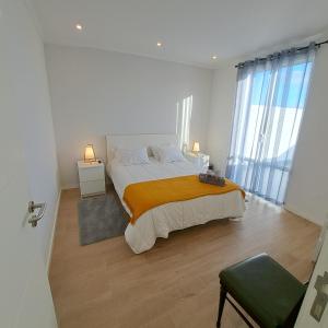 ein weißes Schlafzimmer mit einem großen Bett mit orangefarbener Decke in der Unterkunft Hamilton House in Vila Franca do Campo