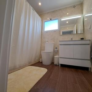 ein Bad mit einem WC, einem Waschbecken und einem Fenster in der Unterkunft Hamilton House in Vila Franca do Campo
