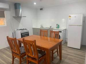 a kitchen with a wooden table and chairs and a refrigerator at Lovely large studio in canning vale in Perth