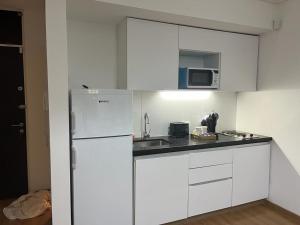 uma cozinha com armários brancos e um frigorífico branco em Apart Archipiélago em Rosário