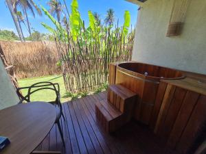 a wooden deck with a tub and a table and chair at Pousada Noah Noah Milagres in São Miguel dos Milagres