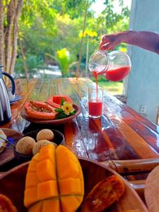 une personne versant du jus dans un verre sur une table avec de la nourriture dans l'établissement Odoyá Corumbau, à Corumbau