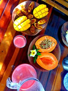 drewniany stół z dwoma talerzami jedzenia i owoców w obiekcie Odoyá Corumbau w mieście Corumbau