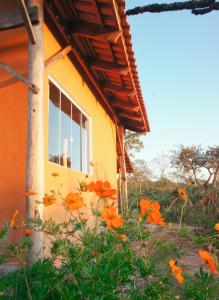 a window of a house with flowers in front of it at Chalé jatobá, venha viver essa experiência!!! in Alto Paraíso de Goiás +6 photos