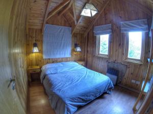 a bedroom with a bed in a wooden cabin at AWEN in Lago Meliquina