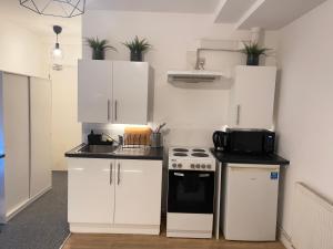 a kitchen with white cabinets and a stove at Comfortable modern (SMART) Studio in Walthamstow. in London