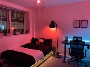 Habitación de color rosa con cama y escritorio. en Comfortable modern (SMART) Studio in Walthamstow. en Londres