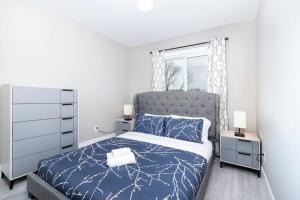a bedroom with a blue bed and a window at Modern & Stylish 2-Bedroom Unit in Edmonton