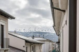 a view of a snowy mountain from between two buildings at B&B CORSO VITTORIO EMANUELE - Nel pieno centro storico in LʼAquila