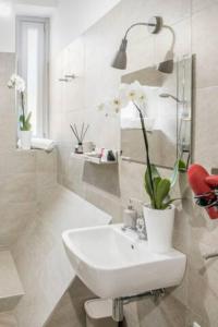 a white bathroom with a sink and a red chair at B&B CORSO VITTORIO EMANUELE - Nel pieno centro storico in LʼAquila