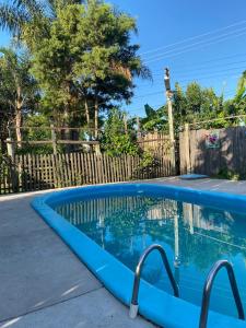 una piscina azul junto a una valla de madera en Pousada Neide, en São Gabriel