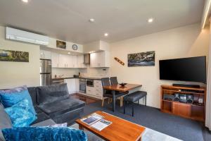 a living room with a couch and a tv and a table at Lantern 1 Bedroom Balcony with mountain View in Thredbo