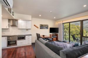a kitchen and living room with a couch and a table at Lantern 1 Bedroom Balcony with mountain View in Thredbo