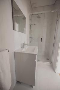 a white bathroom with a sink and a shower at Albina's Guest House in Leça da Palmeira