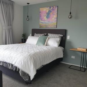 una camera da letto con letto, lenzuola e cuscini bianchi di Piwakawaka Suite a Balclutha