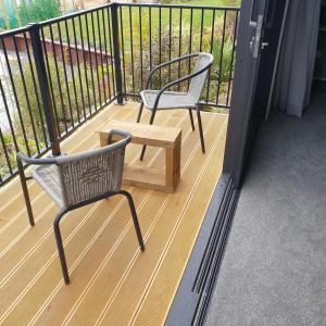 two chairs and a wooden table on a balcony at Piwakawaka Suite in Balclutha