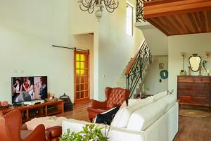 a living room with a white couch and a tv at Linda vista para as montanhas a 5 min da cidade in Santo Antônio do Pinhal